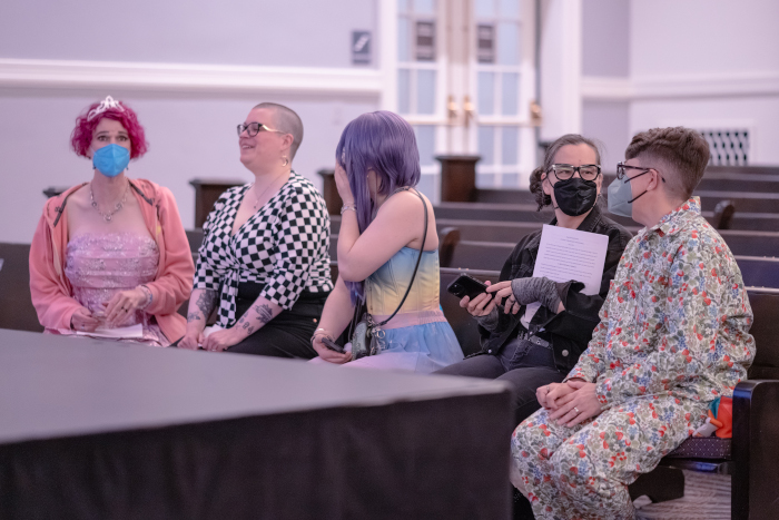 five mirthful looking writers on a church pew, chatting