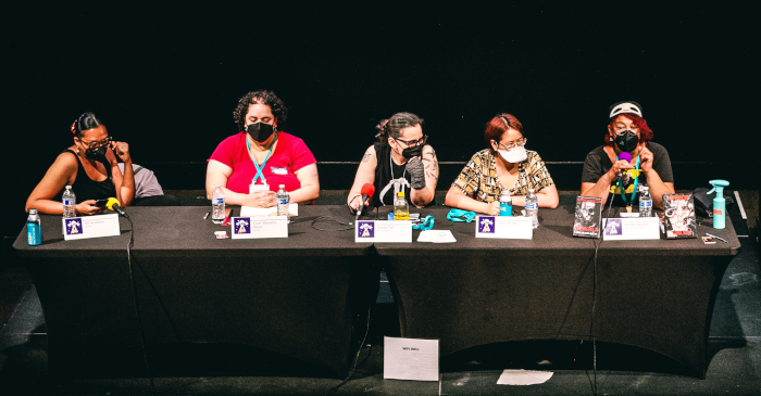 five BIPOC authors seated at a panel table with a black background